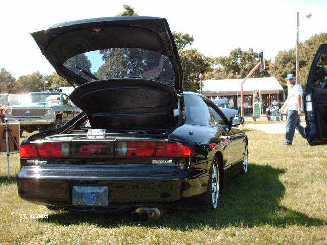 Black Mazda Probe GT with trunk and driver door open, parked on grass