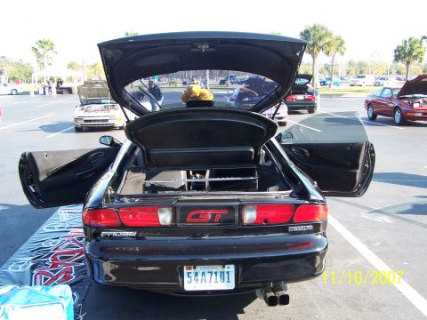 1995 Ford Probe - Rear view of a black 1995 Ford Probe GT, its open trunk and doors, with other vehicles visible in the background.