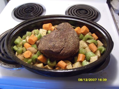 1989 Ford Bronco - A pot roast with chopped carrots and celery sits in a roasting pan on a white stovetop.