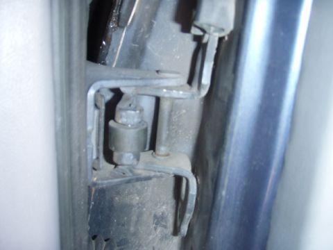 1995 Ford F-150 - Close-up of a vehicle's door hinge mechanism, showing a bolt and metal bracket.
