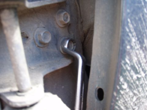 1995 Ford F-150 - A wrench is used to tighten a bolt on a vehicle's door hinge assembly.