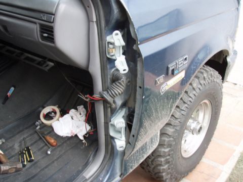 1995 Ford F-150 - The door jamb of a 1995 Ford F-150 shows exposed wiring and new hinges during a repair.