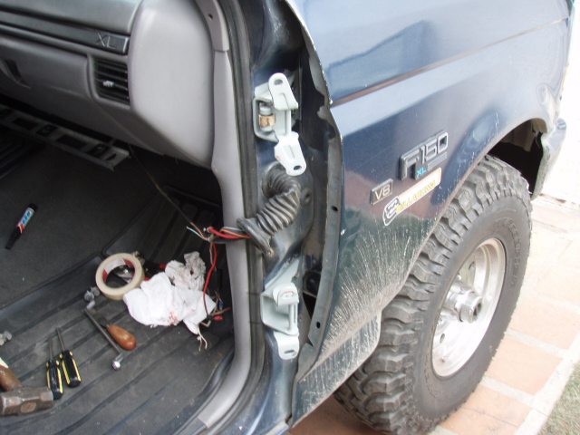 Door hinge area of a 1995 Ford F-150 with tools and wiring visible