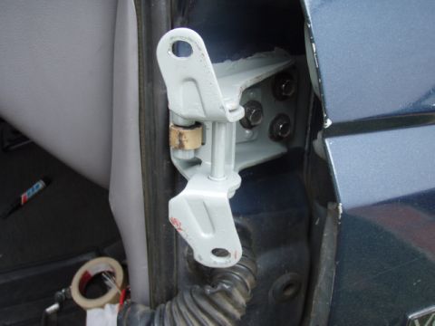 1995 Ford F-150 - Close-up of a freshly painted light-gray door hinge assembly bolted to the A-pillar of a dark teal vehicle with the door open, showing the…
