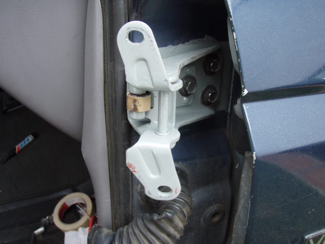 Freshly painted gray door hinge bolted to the pillar of a dark teal truck