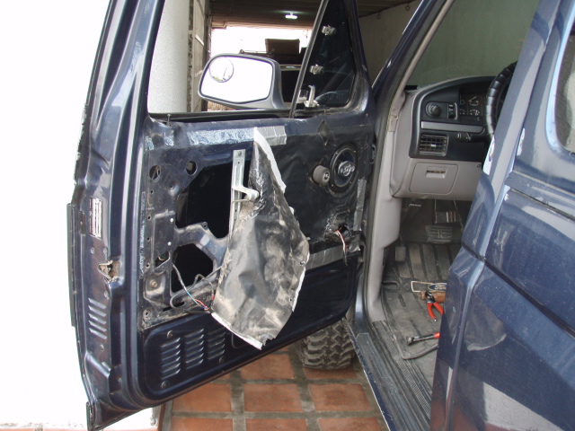 Dark blue truck door interior with removed panel, wires exposed, and a side mirror visible