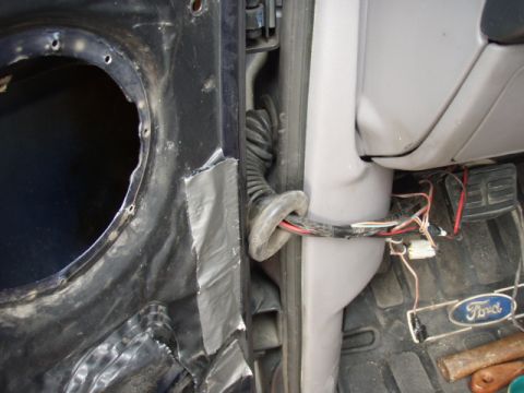 1995 Ford F-150 - Close-up of a Ford emblem and wiring harness inside a vehicle, near the pedals.