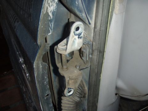 1995 Ford F-150 - Close-up of a door latch and lock rod mechanism exposed on the edge of a blue vehicle door, with the striker bracket, linkage rods and a ri…