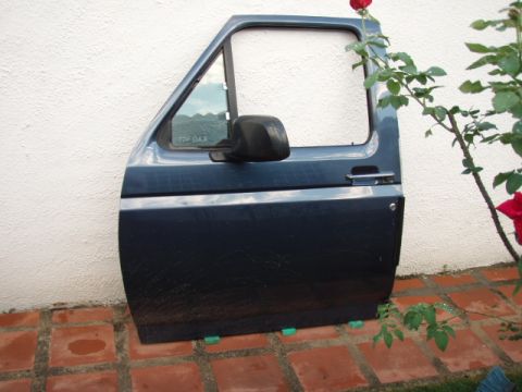 1995 Ford F-150 - A detached dark blue Ford F-150 door is shown leaning against a textured white wall, with rose bushes nearby.