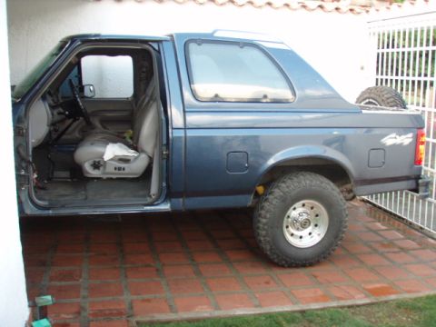 1995 Ford F-150 - Side view of a blue 1995 Ford Bronco, showing the interior with the driver's door ajar.