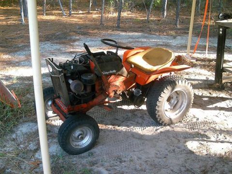 1986 Ford Bronco - An orange riding lawn mower sits outdoors with its engine exposed and seat showing wear.