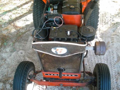 1986 Ford Bronco - Front view of an orange lawn tractor's engine, a mesh grille and visible 'LANDLORD' text on the chassis.