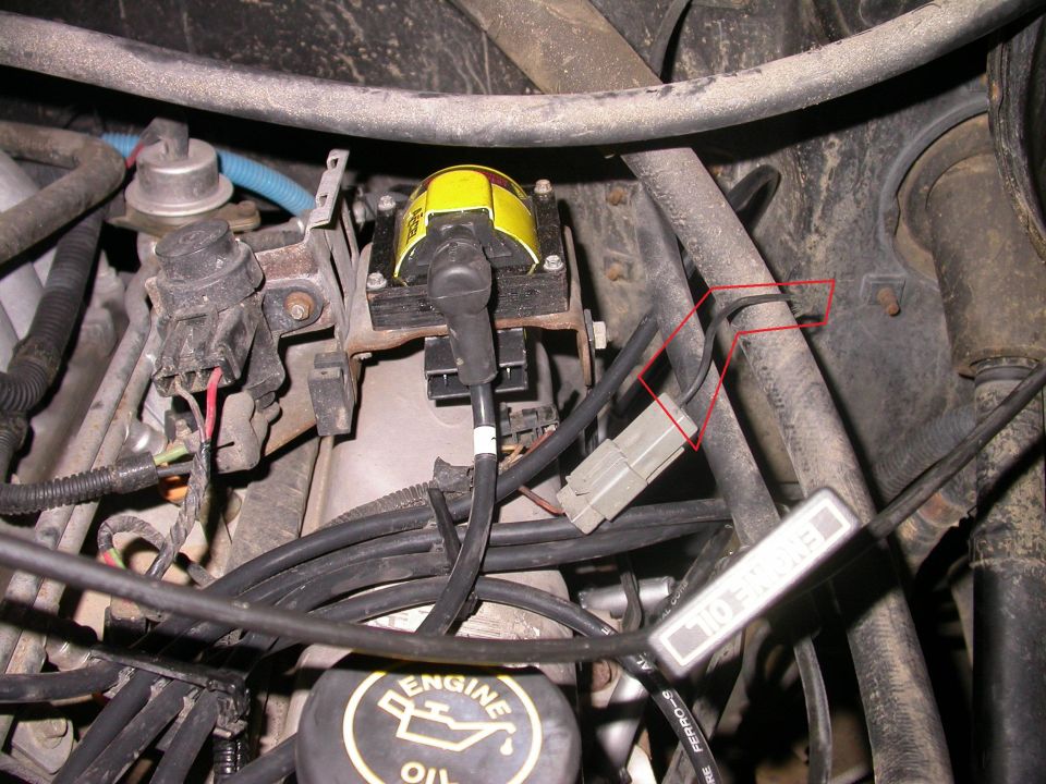 Engine bay with yellow ignition coil and red-outlined gray connector