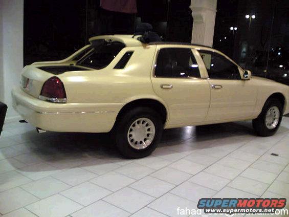 Cream sedan with a custom bed cover and rear spoiler, seen from the side