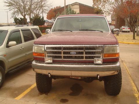 1992 Ford Bronco - A maroon Ford truck is parked outside next to a silver SUV on a cloudy day.
