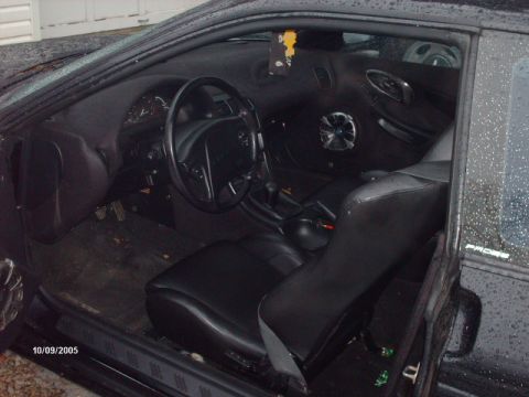 1995 Ford Probe - Interior view of a black car, leather seats and a prominent aftermarket speaker on the door panel.