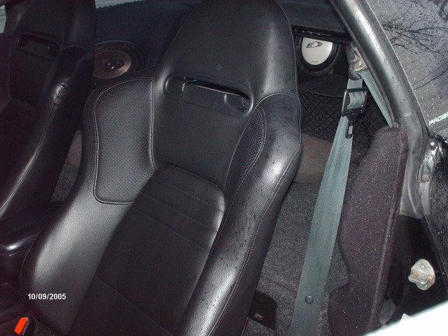 Interior shot of a car showing black racing seats, speakers, and a seatbelt. Date stamp reads 10/09/2005