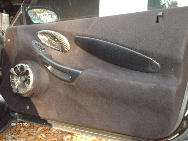 Car door panel with aftermarket speaker and carbon fiber accents