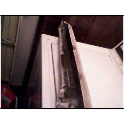Torn weather stripping on a white appliance, possibly a washing machine or dryer