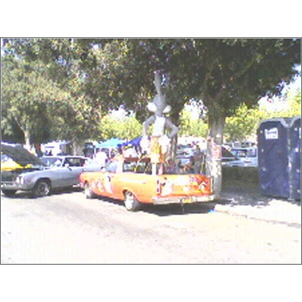 Orange pickup truck with cartoon character, rear view. Appears to be a 1970s model