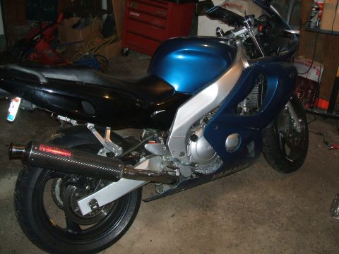 2004 Yamaha FZR600 - A blue and black motorcycle is parked indoors, an aftermarket exhaust system and a metallic silver frame.