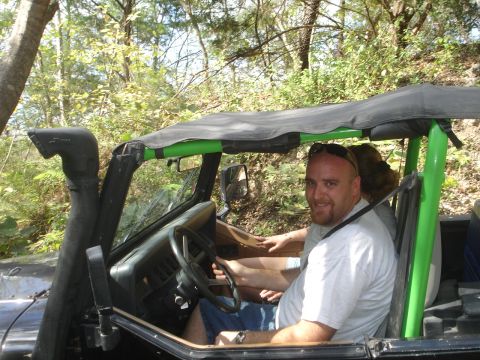 1989 Ford Bronco - A man smiles from the driver's seat of a Jeep Wrangler equipped with a snorkel, suggesting off-road use.