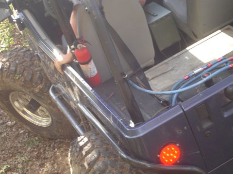 1989 Ford Bronco - A fire extinguisher is mounted inside a modified Jeep, with visible hoses and a storage box in the rear.