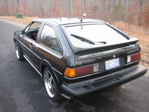 1987 Volkswagen Scirocco - Rear view of a black 1987 Volkswagen Scirocco parked on a paved road with trees in the background.