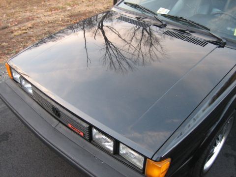 1987 Volkswagen Scirocco - Front view of a 1987 Volkswagen Scirocco, showing the hood and grille with tree reflections.