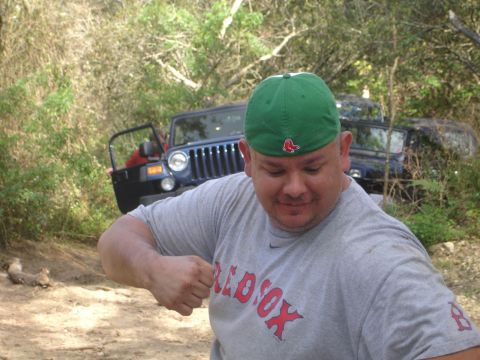 1989 Ford Bronco - A man poses in front of a Jeep, which appears to be off-roading in a wooded area.