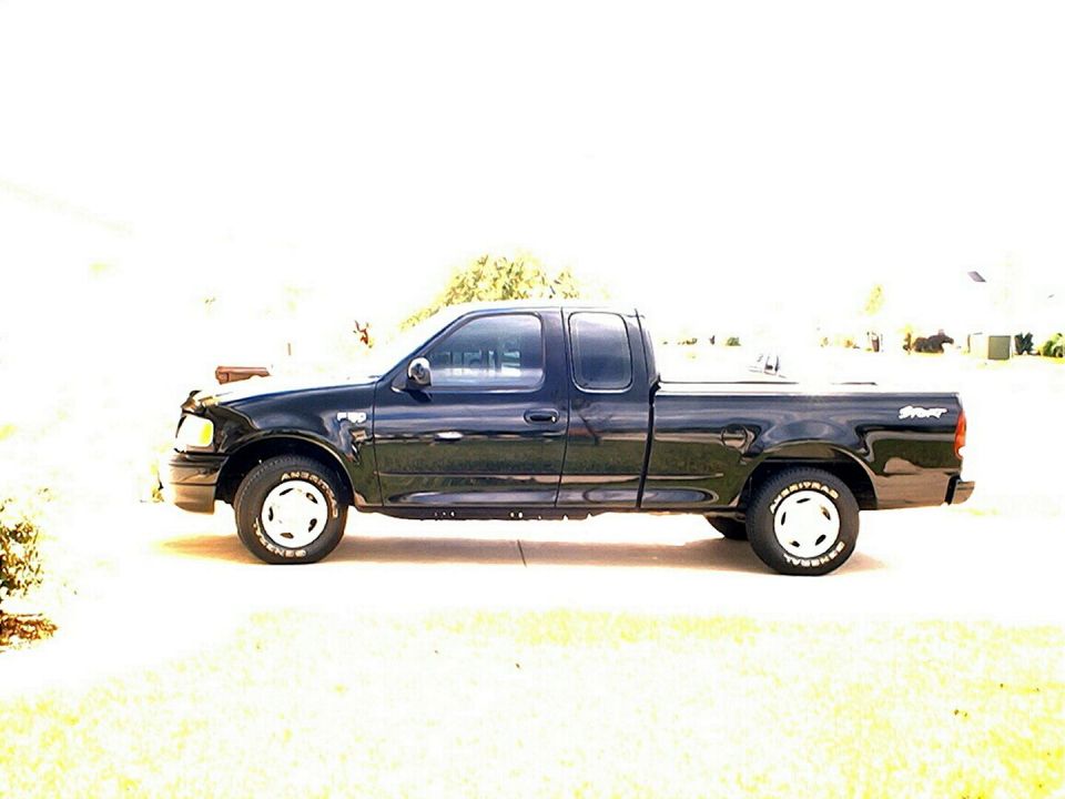 Black Ford F-150 extended-cab Sport pickup, driver-side profile on white steel wheels
