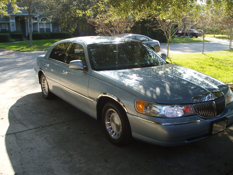 Light blue 1998 Lincoln Town Car parked on a driveway, front 3/4 view