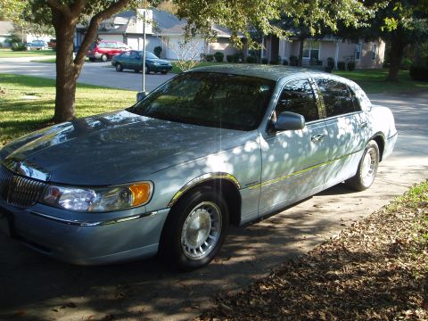 1998 Lincoln Town Car - A 1998 Lincoln Town Car is parked on a residential driveway under a tree.