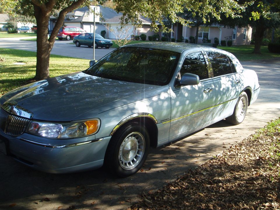 Light blue 1998 Lincoln Town Car parked on a driveway, seen from the front quarter