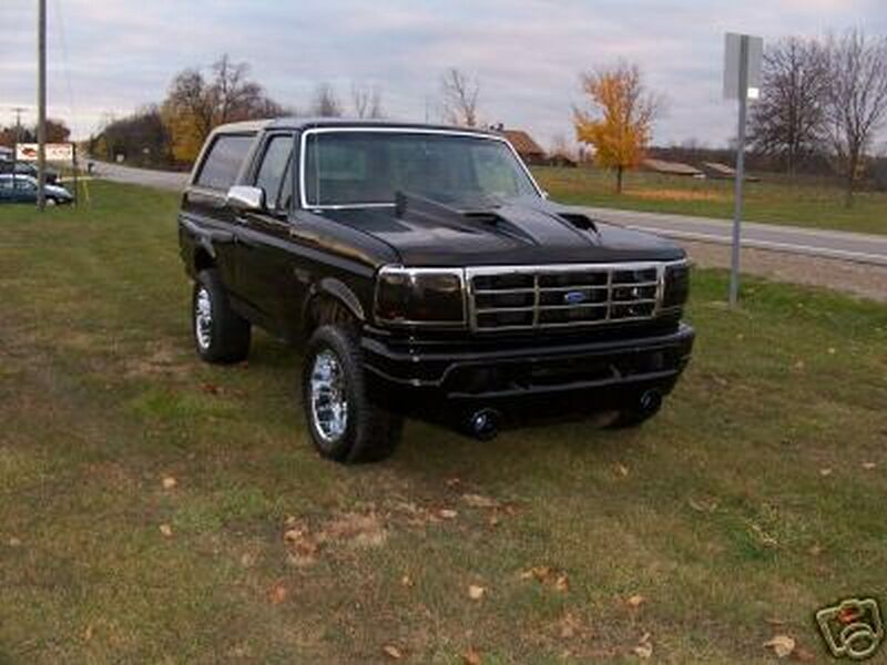 Lifted black Ford Bronco front three-quarter view on grass