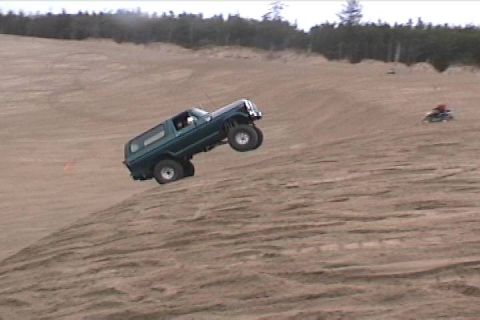 1979 Ford Bronco - A green 1979 Ford Bronco navigates a steep sand dune, with another vehicle visible in the background.