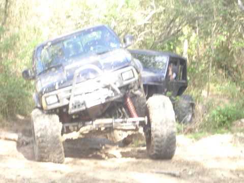 1989 Ford Bronco - Two modified off-road vehicles navigate a muddy terrain, their capabilities.