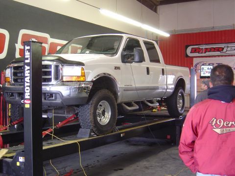 1996 Ford F-250 - A white pickup truck is positioned on a dynamometer for testing, with its front end prominently displayed.