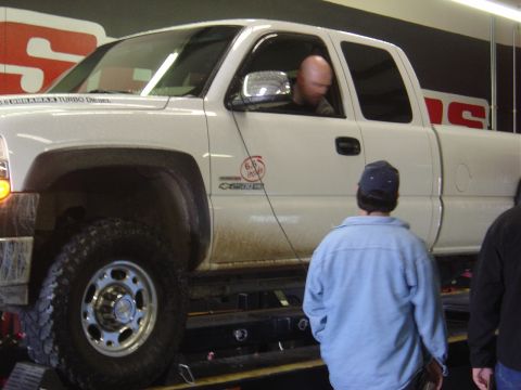 1996 Ford F-250 - A white pickup truck is positioned on a dynamometer, with a driver seated inside and onlookers observing.