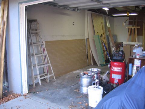 1989 Ford Bronco - A cluttered garage scene with various building materials and tools, including an air compressor and spare rims.