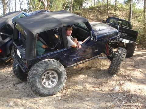 1989 Ford Bronco - Modified Jeep Wrangler tackling rough terrain with another vehicle in the background.