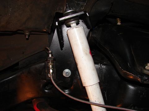 1973 Ford Ranchero - Under-car close-up of a white gas shock absorber stem-mounted through a black fabricated bracket with fresh bushings and washers, next to a…