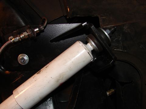 1973 Ford Ranchero - Tight underbody shot of a white shock absorber bolted to a black-painted fabricated shock mount bracket on a vehicle frame, with the stud-a…