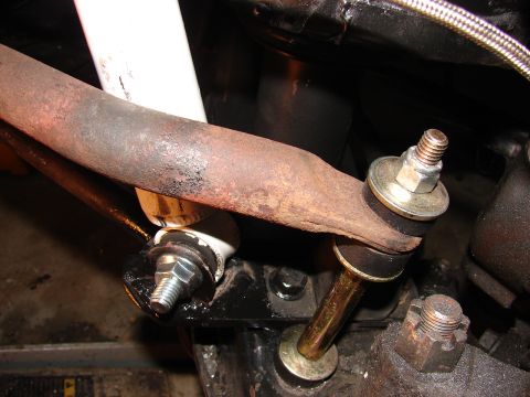 1973 Ford Ranchero - Close-up under a vehicle showing a rusty steering linkage arm joined by new zinc-plated tie-rod/drag-link ends with fresh nuts and washers.…