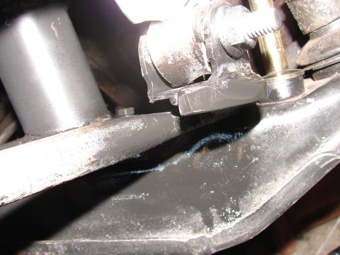 1973 Ford Ranchero - Tight flash close-up of suspension and chassis hardware, showing a bare steel arm passing over a black painted frame bracket with a yellow…
