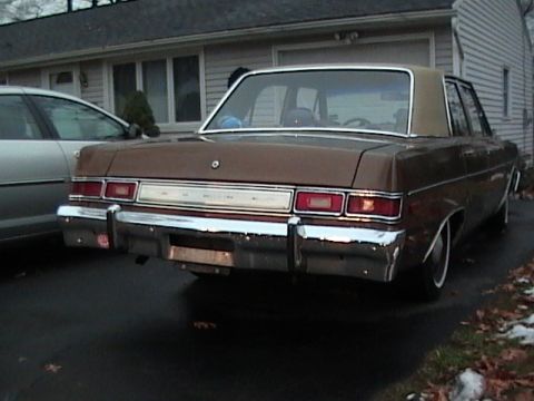 1990 Ford Bronco - Rear view of a brown sedan with a chrome bumper and dual taillights.