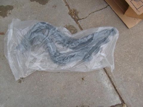 1995 Ford C-150 (Centurion Conversions) - Unidentified automotive part in plastic wrap on concrete surface.