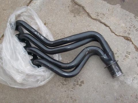 1995 Ford C-150 (Centurion Conversions) - A set of black exhaust headers is shown resting on a concrete surface, partially covered by a plastic bag.