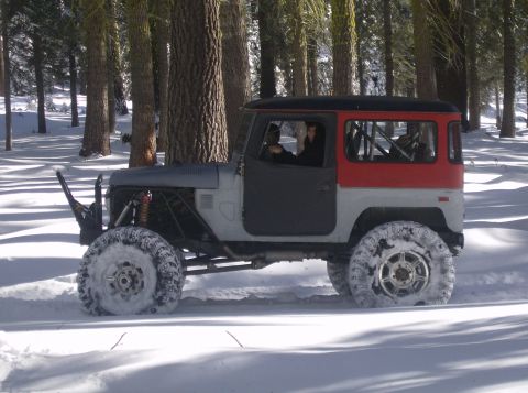 1986 Ford Bronco - A heavily modified Toyota Land Cruiser FJ40 navigates a snowy forest road.