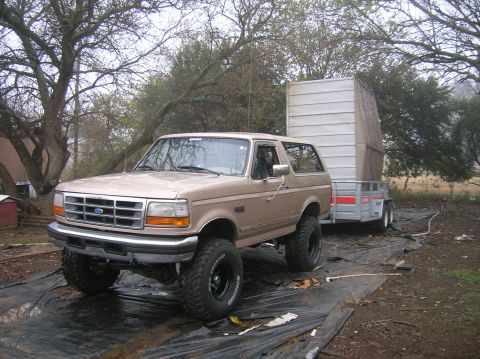 1996 Ford Bronco - A tan Ford Bronco with a lifted suspension tows a silver trailer in an outdoor setting.